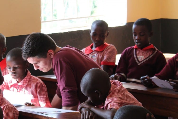  Justin, a volunteer, with students reading letters from their sponsors